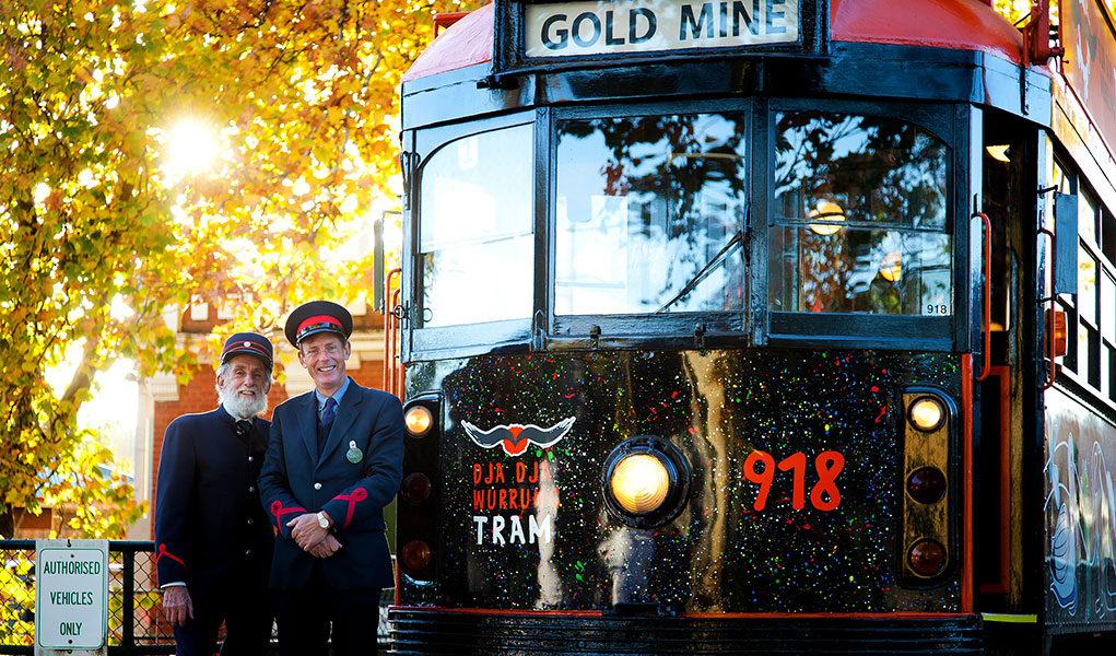 Two Tram Drivers standing in front of the Dja Dja Wurrung Tram with Autumn Leaves in the background